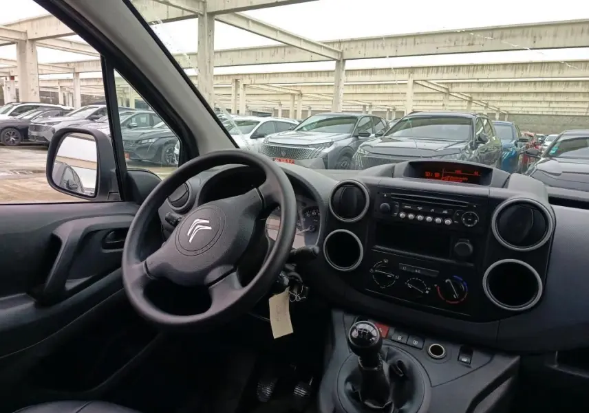 Vue intérieure côté conducteur du Citroën Berlingo blanc 2018, montrant le volant, tableau de bord et levier de vitesses manuel.