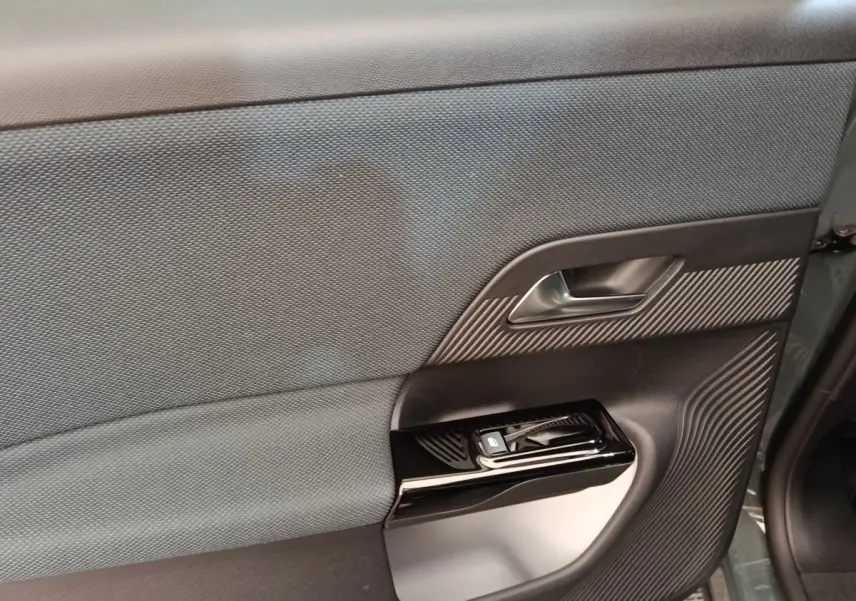 Gros plan sur la porte intérieure côté gauche du Citroën C5 hybride vert 2026 avec garniture textile et commandes de fenêtre.