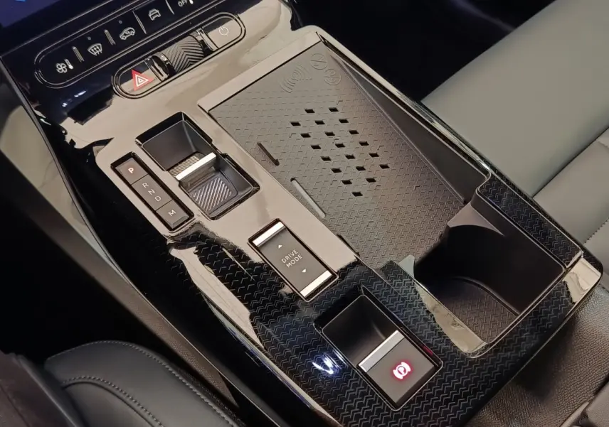 Gros plan sur la console centrale noire brillante de la Citroën C5 hybride avec commandes de boîte auto et recharge sans fil.