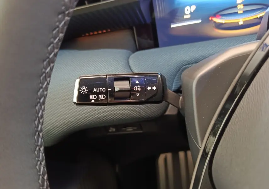 Gros plan sur la commande des feux et clignotants côté gauche du volant dans l’habitacle du Citroën C5 Hybride vert.