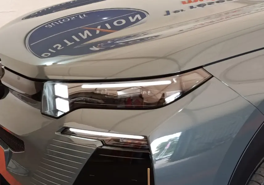 Gros plan sur le phare avant droit du Citroën C5 hybride vert 2026 avec détails lumineux modernes et carrosserie brillante.