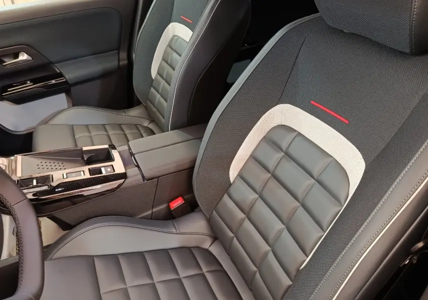 Vue intérieure rapprochée des sièges avant gris et noir avec surpiqûres et accoudoir central de la Citroën C5 Hybride 2026.