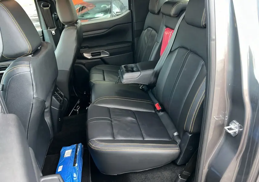Vue intérieure côté droit des sièges arrière en cuir noir avec surpiqûres jaunes du Ford Ranger 2025 gris carbone Wildtrak Plus.