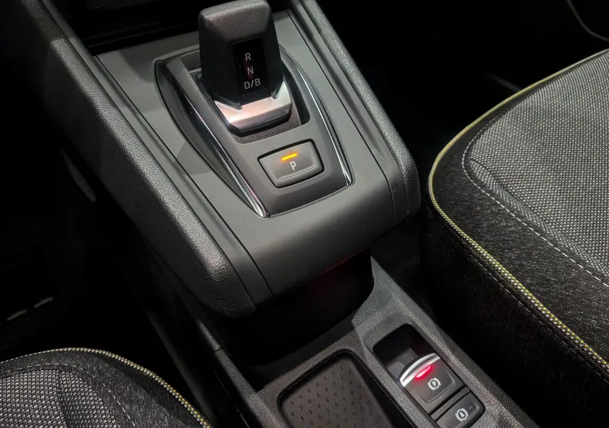 Gros plan sur la console centrale du Renault Captur hybride 2025, montrant le levier de vitesses automatique et les sièges en tissu noir.