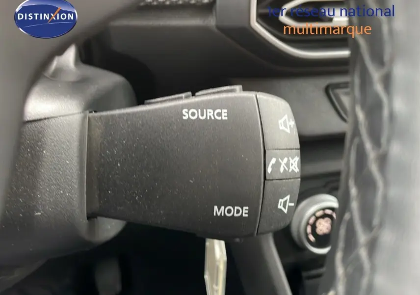 Gros plan sur la commande au volant du Dacia Jogger gris schiste, avec boutons source et mode visibles.
