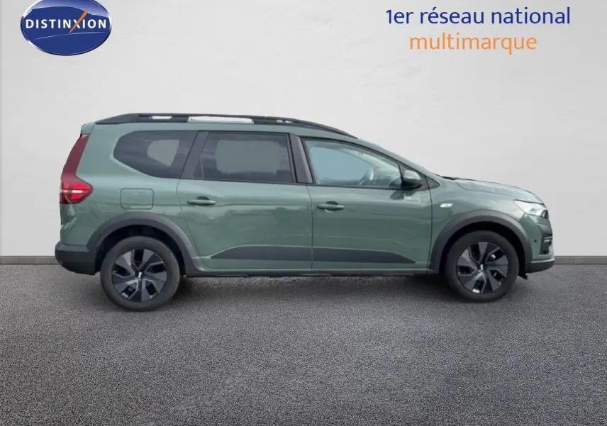 Vue latérale droite d'un Dacia Jogger gris schiste métal avec jantes noires et barres de toit noires.