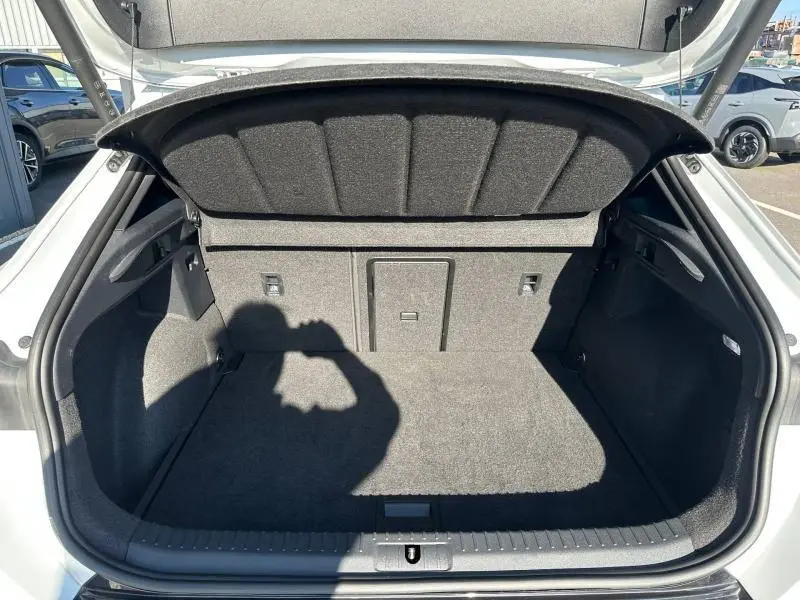 Coffre ouvert vu de l'arrière d'un CUPRA Formentor blanc Nevada métallisé, montrant l'espace de chargement vide et doublure grise.