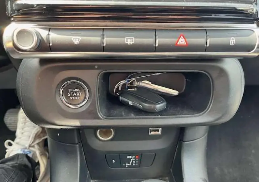 Vue rapprochée de la console centrale de la Citroën C3 2023 avec bouton start/stop et clés posées dans le rangement noir.