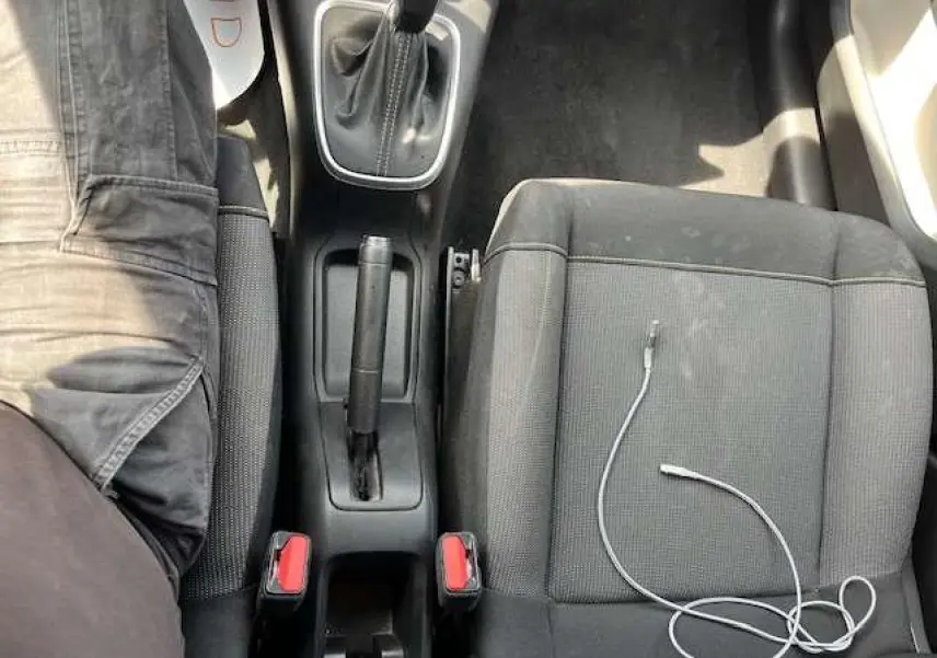 Vue plongeante sur la console centrale et les sièges avant noirs de la Citroën C3 2023, câble USB posé sur le siège passager.