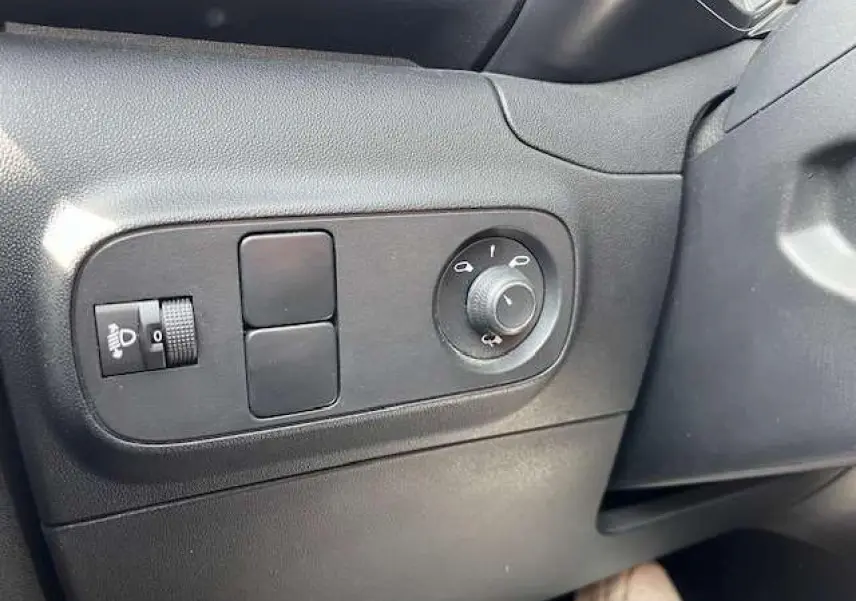 Gros plan sur les commandes de réglage des rétroviseurs et des phares dans l'habitacle noir du Citroën C3 2023.