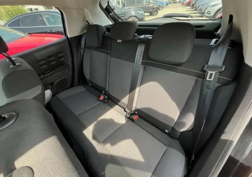 Vue intérieure de la banquette arrière noire de la Citroën C3 2023, avec ceintures et appuie-têtes visibles.