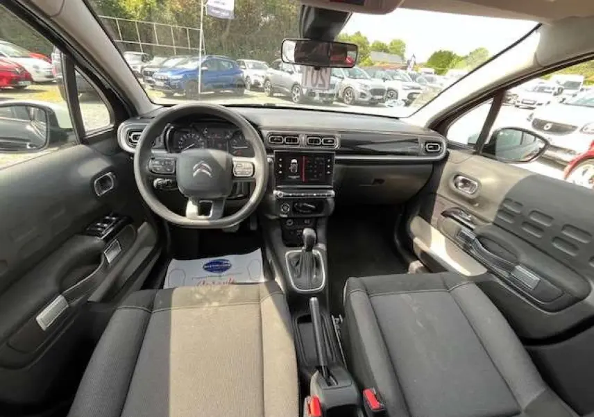 Intérieur de la Citroën C3 2023 vu de face, avec tableau de bord noir et sièges tissu gris foncé.