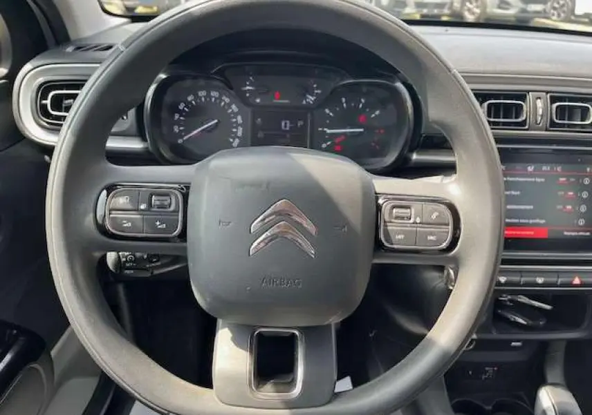 Vue centrée sur le volant noir de la Citroën C3 2023 avec tableau de bord et écran tactile en arrière-plan.
