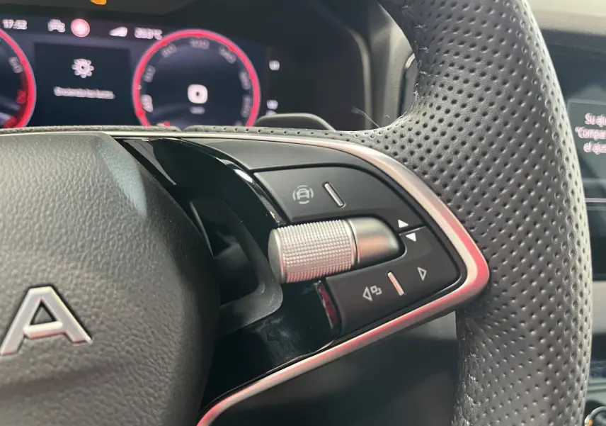 Gros plan sur le volant perforé noir du Skoda Karoq 2025 avec commandes multifonctions et tableau de bord digital rouge.