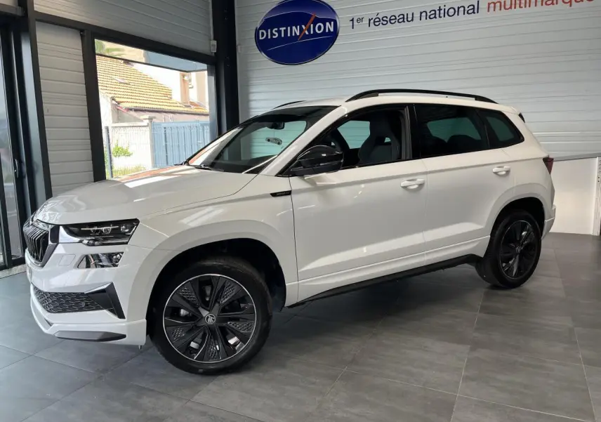 SUV SKODA KAROQ blanc en vue de profil côté gauche, avec jantes noires et détails noirs Sportline visibles.