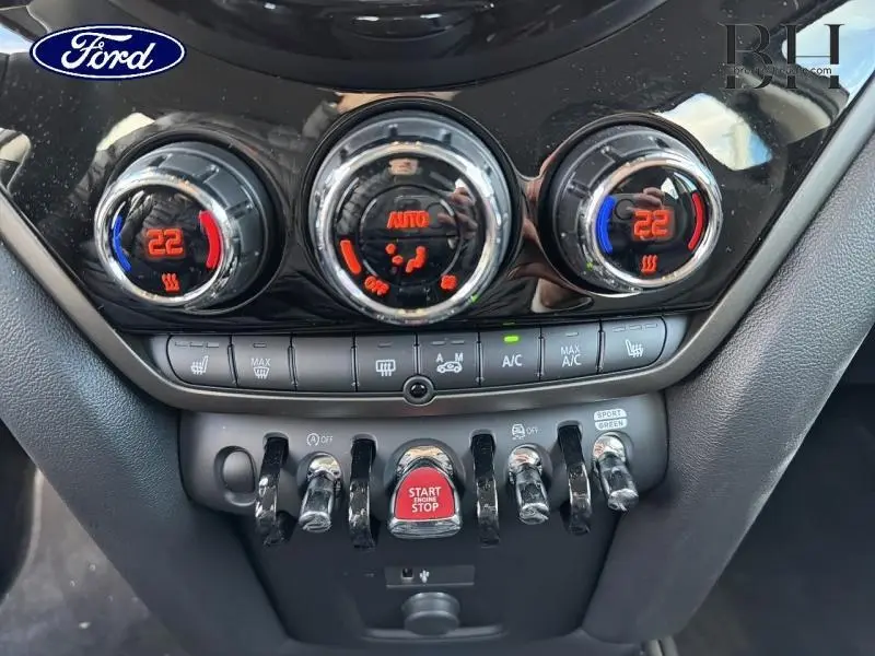 Gros plan sur la console centrale du MINI Countryman 2023 avec commandes climatisation et bouton start/stop rouge.