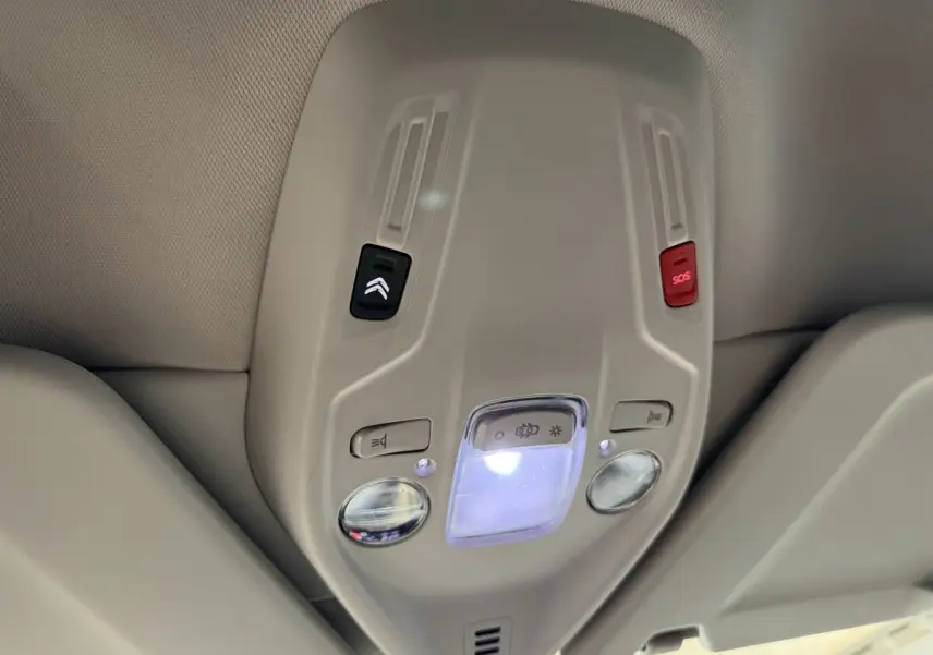 Plafonnier intérieur beige avec commandes d’éclairage et bouton SOS dans un Citroën C4 Spacetourer noir, vue de dessous.