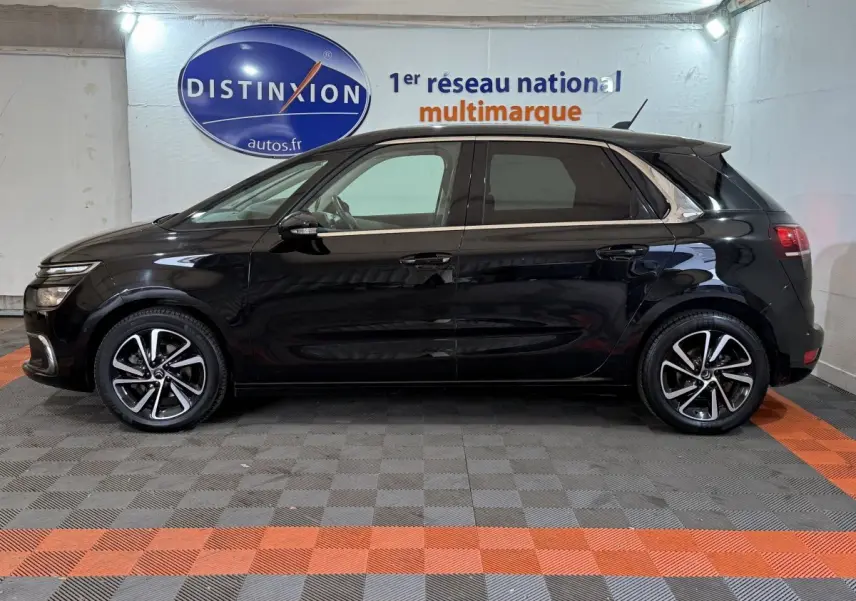 Vue de profil côté gauche d'une Citroën C4 Spacetourer noire 2020 avec jantes alliage bicolores dans un showroom.