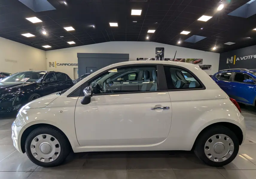 Profil côté gauche d'une Fiat 500 blanche Bossanova 2018 en intérieur, avec rétroviseurs chromés et jantes acier.