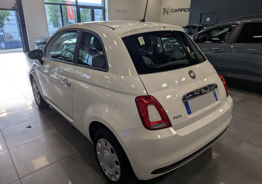 Vue 3/4 arrière droite d'une Fiat 500 blanche Bossanova 2018 dans un showroom, avec feux arrière rouges et jantes acier.