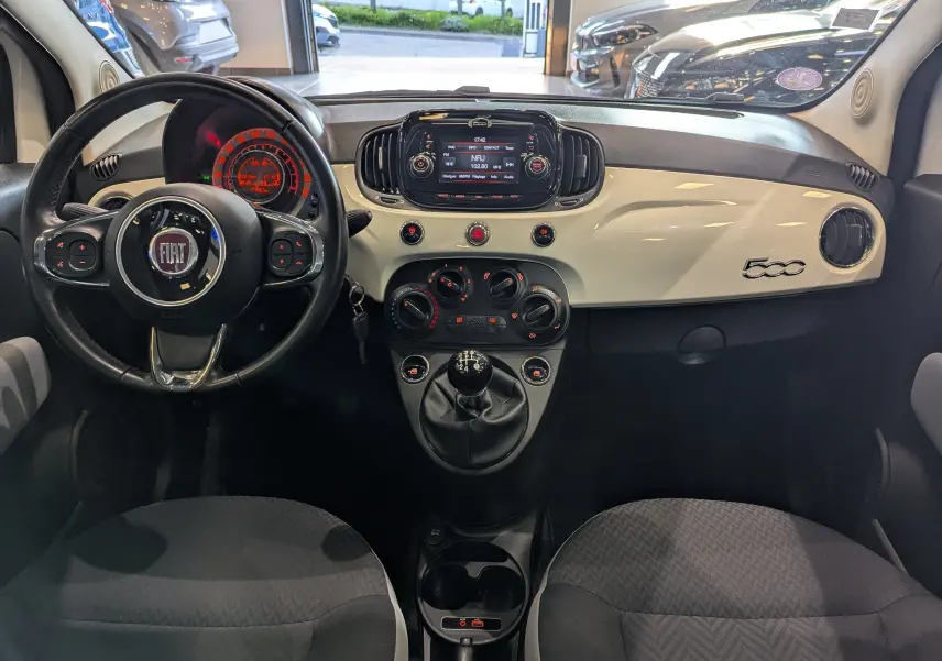 Vue intérieure frontale du tableau de bord blanc Bossanova et volant noir de la Fiat 500 1.2 69 CH Popstar de 2018.