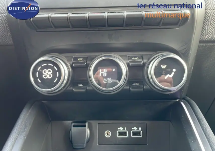 Gros plan sur la console centrale de la Renault Clio rouge Désir Métal, montrant les commandes de climatisation et ports USB.