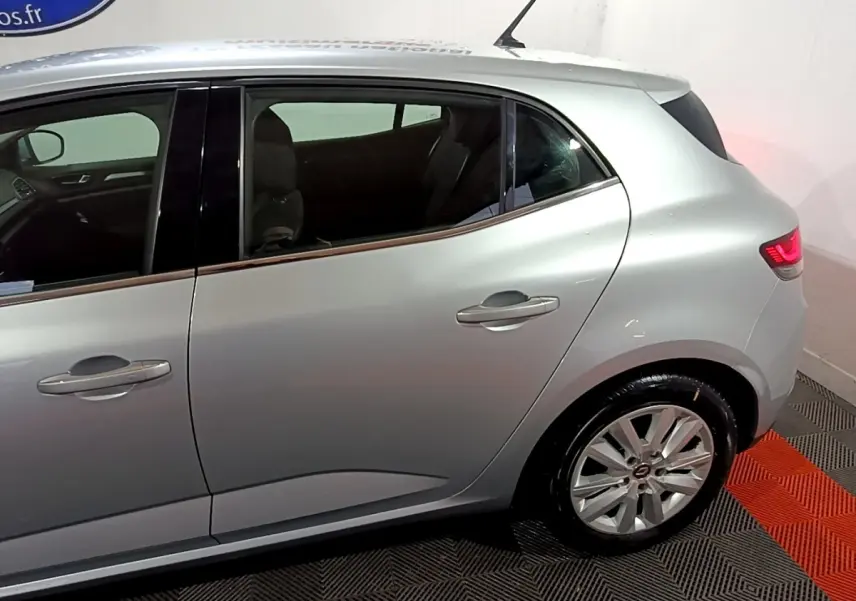 Vue latérale côté droit d'une Renault Mégane Business Blue dCi 115 EDC gris clair avec jantes alliage et feux arrière allumés.