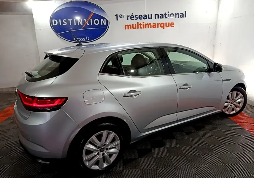 Renault Mégane Business Blue dCi 115 EDC gris clair vue 3/4 arrière droit en intérieur avec feux arrière allumés.