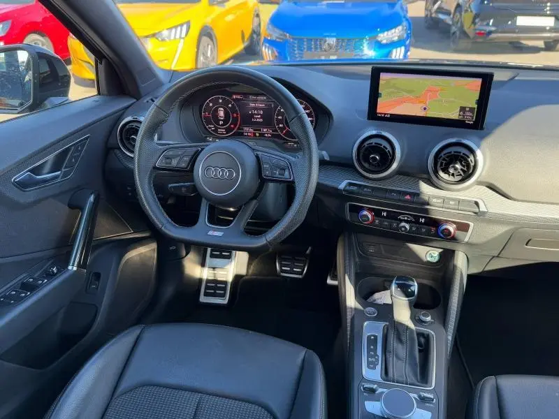 Vue intérieure de l'Audi Q2 2024 S line, montrant le volant sport, tableau de bord numérique et écran GPS central.