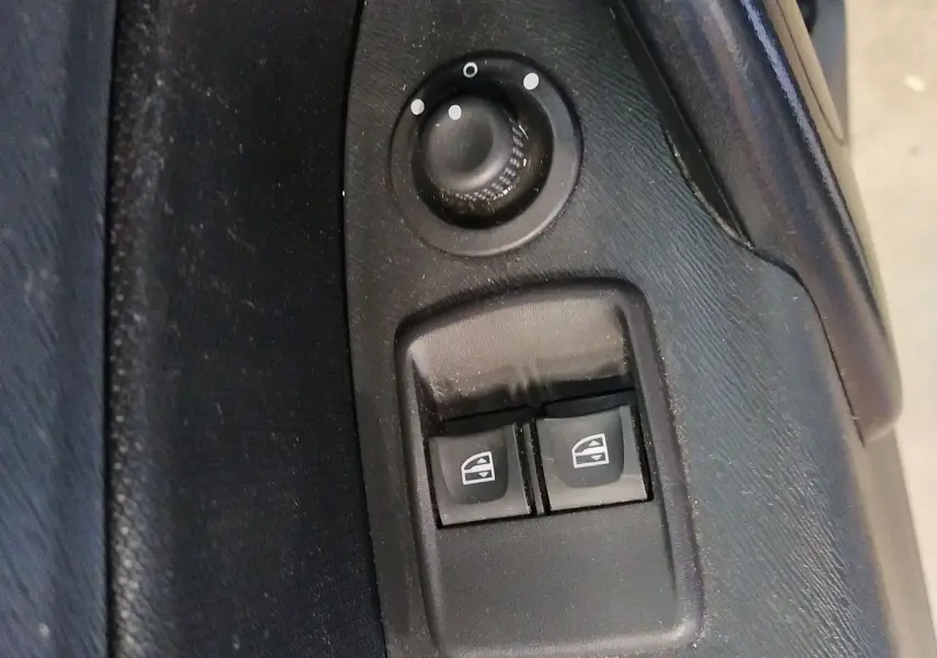 Gros plan sur les commandes de réglage des rétroviseurs et des vitres électriques côté conducteur du Renault Kangoo blanc 2019.