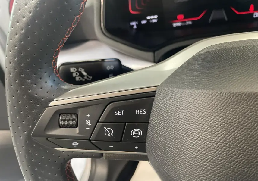 Gros plan sur les commandes du volant sport cuir noir perforé avec surpiqûres rouges du SEAT Arona 2024.