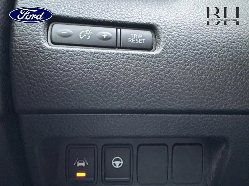Détail du tableau de bord noir du Nissan Qashqai 2018 montrant les boutons de réglage d'éclairage et d'assistance à la conduite.