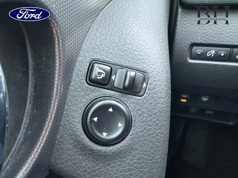 Gros plan sur les commandes de réglage des rétroviseurs noirs dans l'habitacle d'un Nissan Qashqai gris Squale.