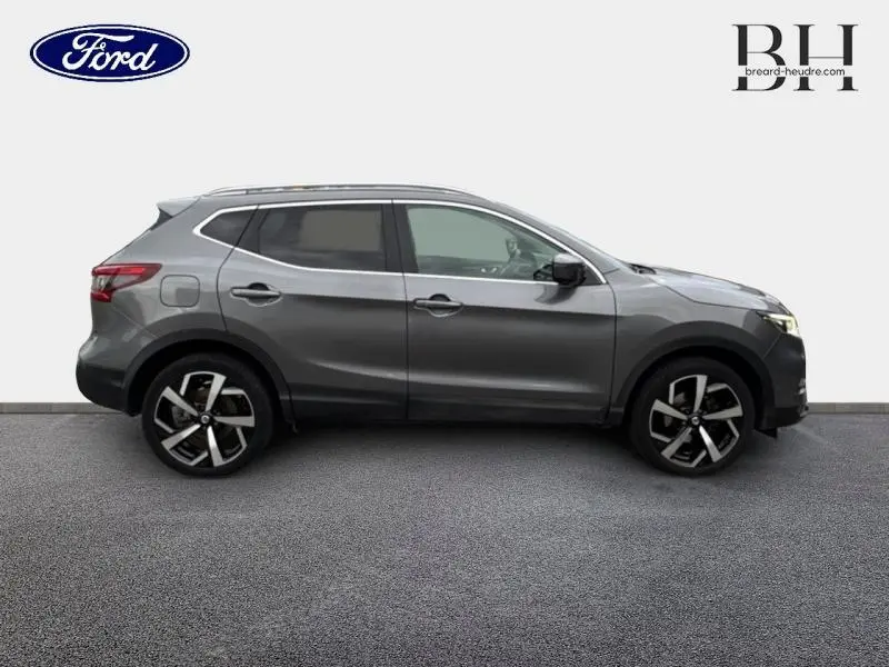 Profil droit d'un Nissan Qashqai gris Squale 2018 avec jantes alliage et vitres teintées sur fond neutre.