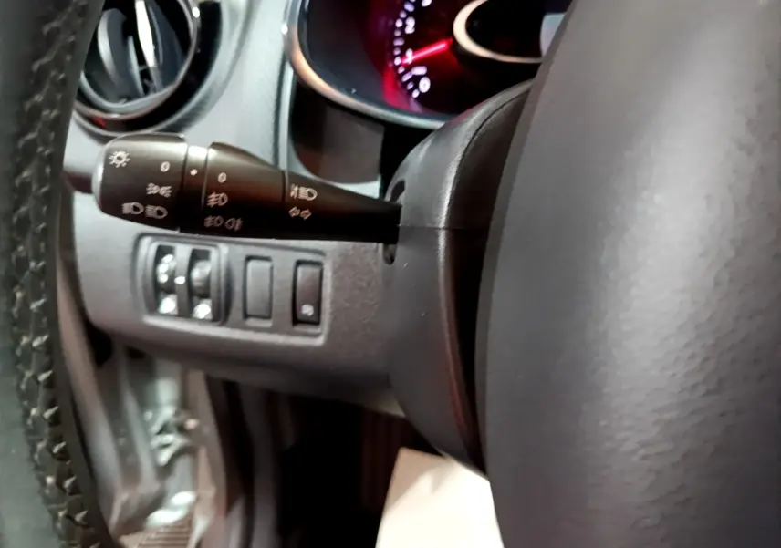 Gros plan sur le volant cuir et la commande des phares à gauche du tableau de bord d’une Renault Clio gris clair 2018.