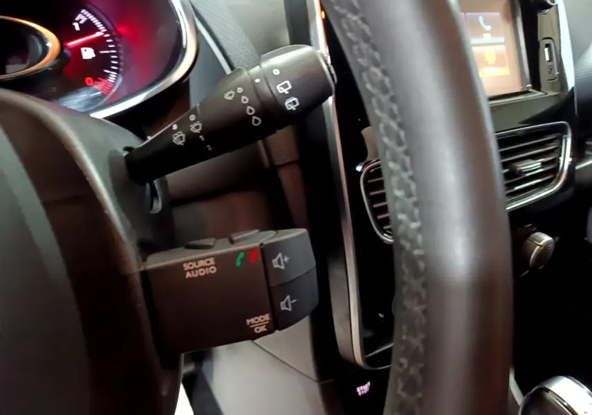 Gros plan intérieur sur le volant cuir et commandes audio au volant d’une Renault Clio Business gris clair de 2018.