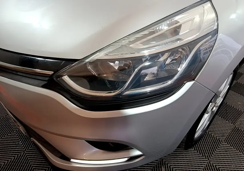 Gros plan sur l'avant droit gris clair de la Renault Clio 2018, mettant en valeur le phare et la calandre chromée.