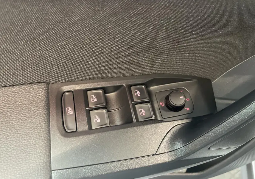 Panneau de commandes des vitres et rétroviseurs côté conducteur dans une SEAT ARONA rouge Passion 2024.