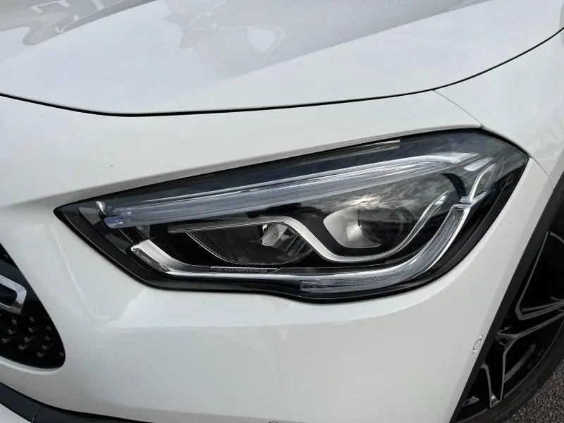 Gros plan sur le phare avant droit LED du Mercedes GLA 200 AMG Line blanc polaire avec jante noire visible.
