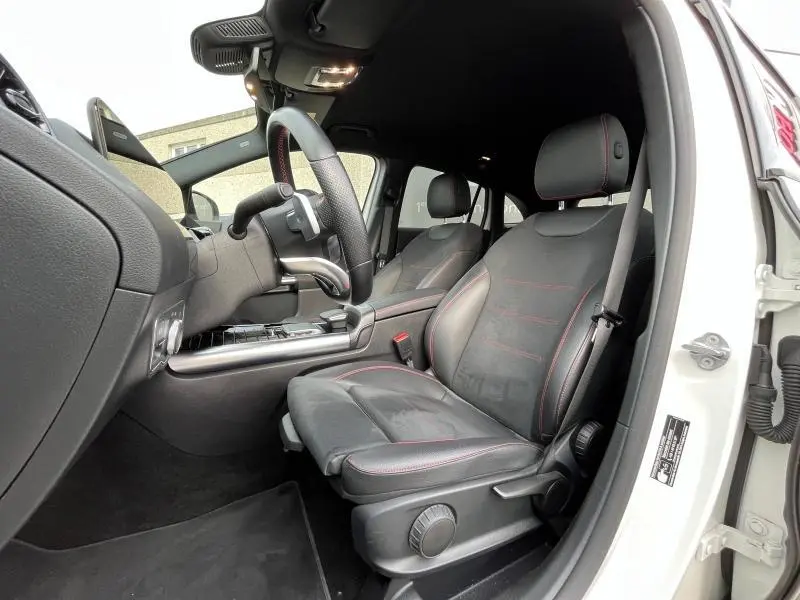 Intérieur avant droit du Mercedes GLA 200 AMG Line 2022, sièges sport noirs avec surpiqûres rouges visibles.