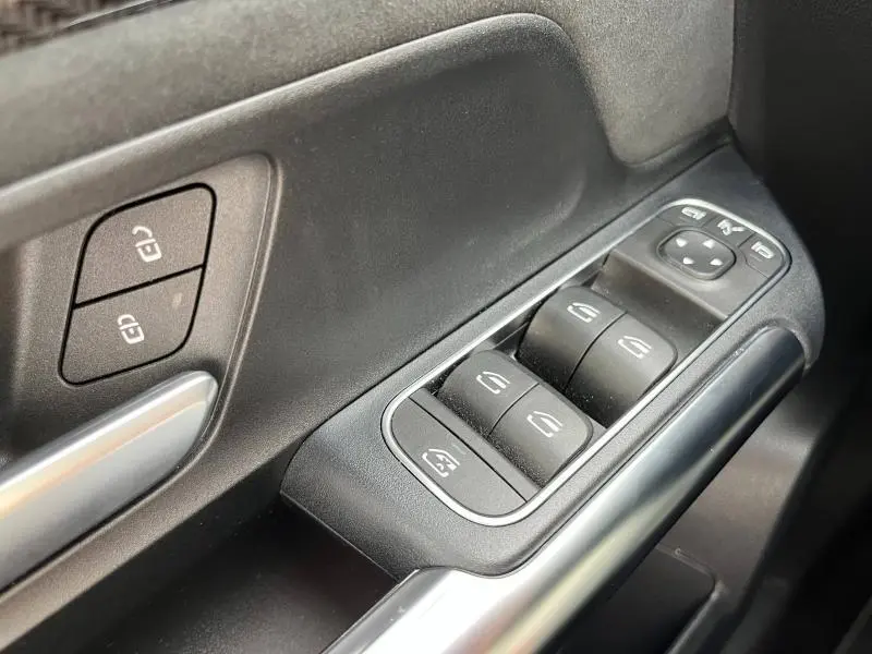 Gros plan sur les commandes des vitres et serrures côté conducteur du Mercedes GLA 200 AMG Line blanc polaire 2022.