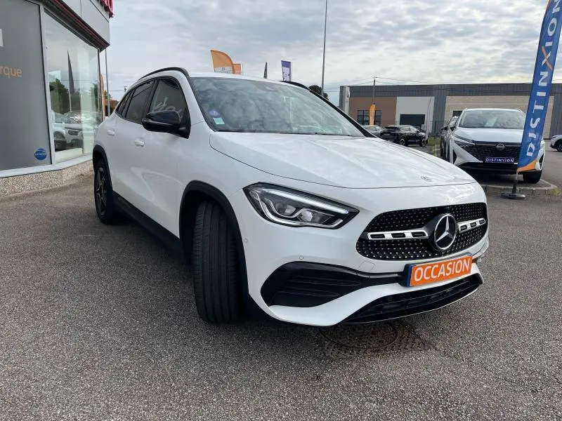 Mercedes GLA 200 AMG Line blanc polaire vu en 3/4 avant droit avec calandre noire et plaque "OCCASION" orange.