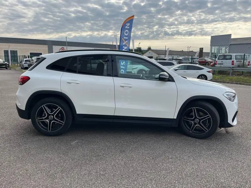Profil côté gauche d'un Mercedes GLA 200 AMG Line blanc polaire avec jantes alliage noires et toit blanc.