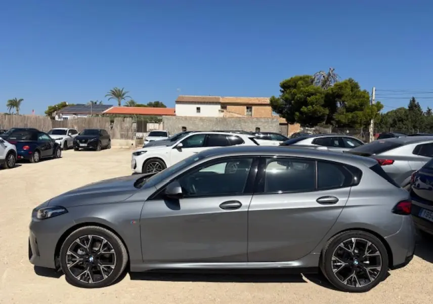 BMW Série 1 118d M Sport gris métallisé vue profil côté gauche sur parking ensoleillé