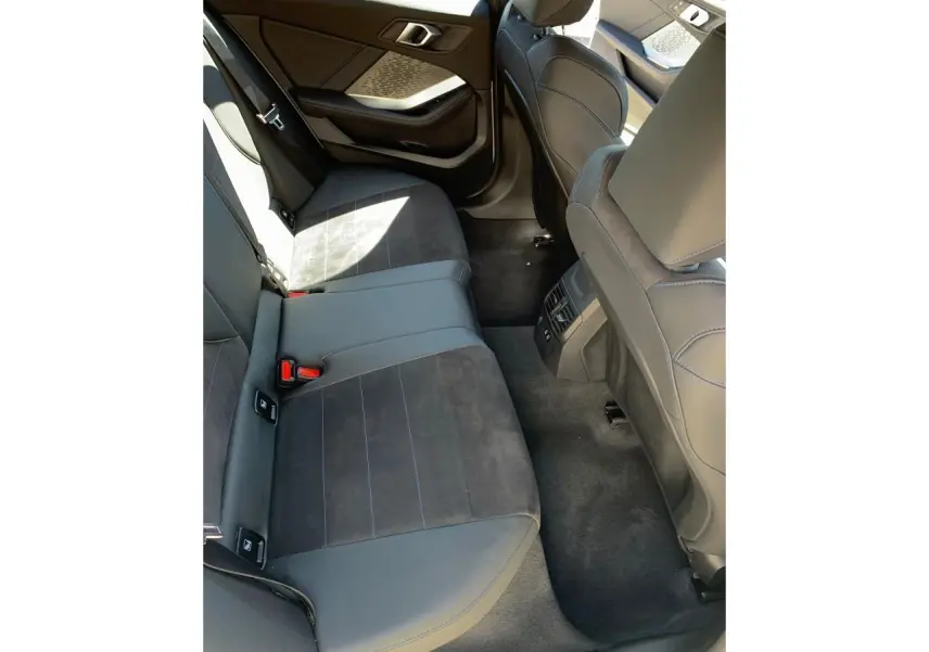 Vue du siège arrière côté gauche de la BMW Série 1 118d M Sport 2025 avec sellerie Alcantara noire et surpiqûres bleues.