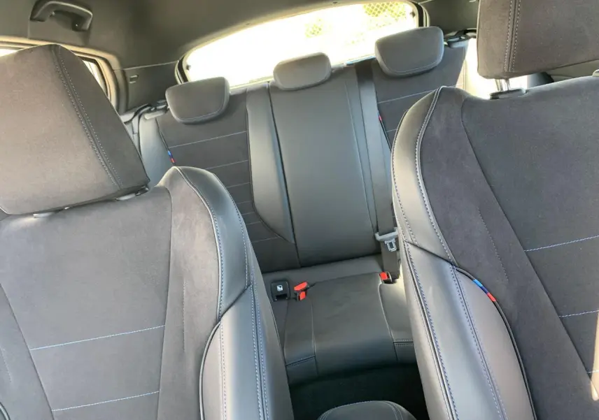 Vue intérieure des sièges avant et arrière en Alcantara noir avec surpiqûres bleues d'une BMW Série 1 118d M Sport.