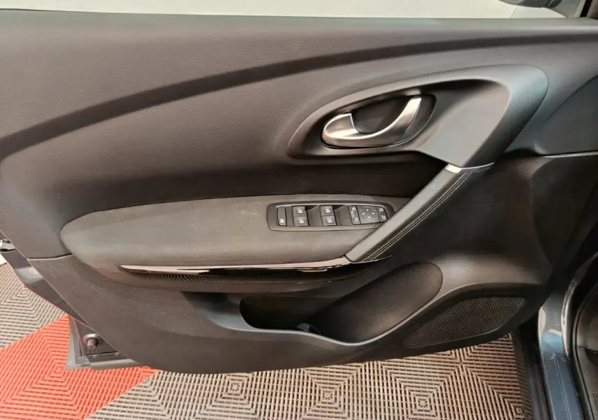 Vue intérieure de la porte avant gauche du Renault Kadjar gris foncé, avec commandes électriques et poignée argentée.