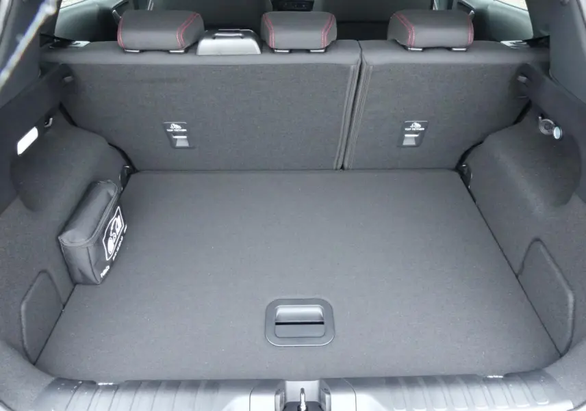 Vue du coffre spacieux et propre du Ford Puma 2025 gris métallisé, avec sièges arrière rabattus et kit de secours visible.