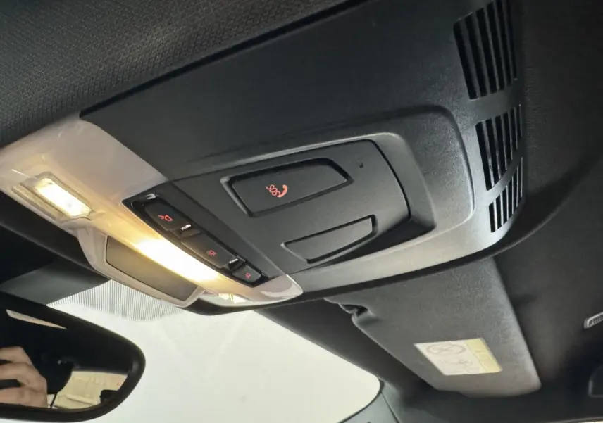 Vue intérieure en plongée du plafonnier noir avec commandes SOS et éclairage allumé d'une BMW X2 bleu hybride rechargeable.
