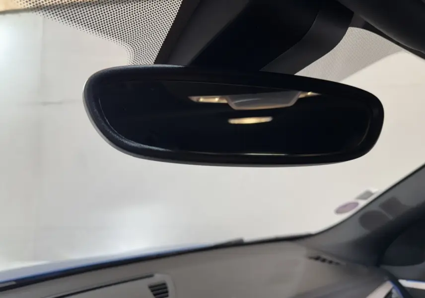 Vue intérieure centrée sur le rétroviseur intérieur d’une BMW X2 bleu, avec tableau de bord gris en arrière-plan.